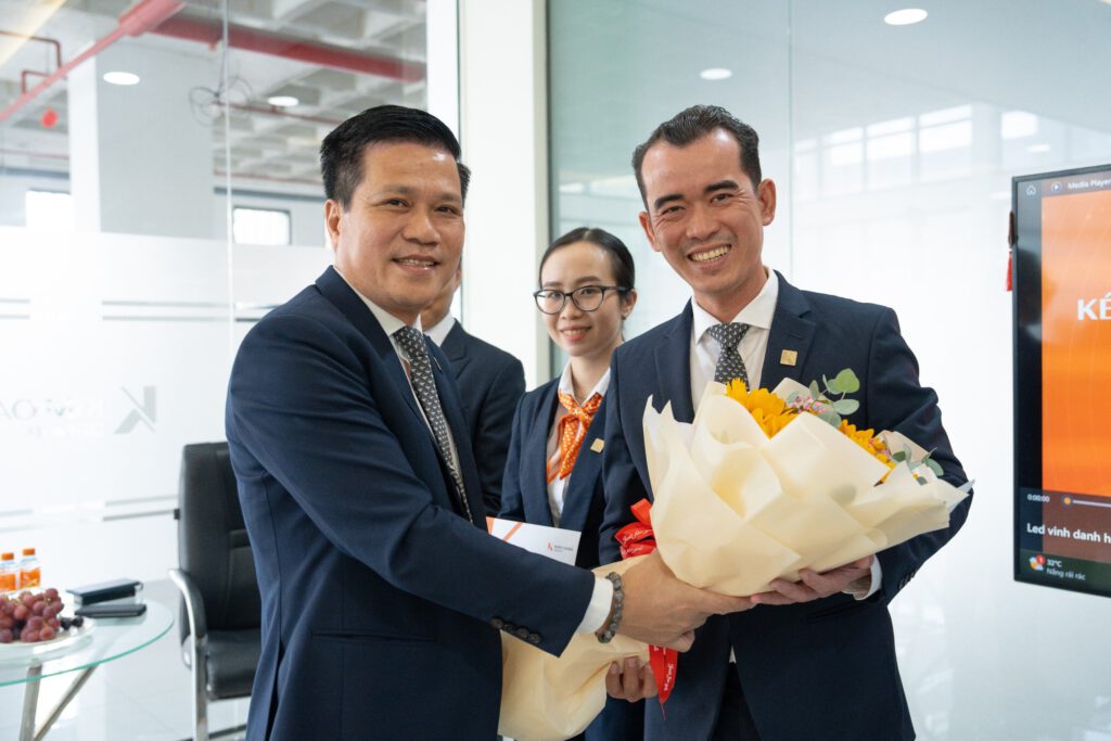 vinh-danh-01-6 Anh Trần Trọng Minh Hoàng – Giám đốc Chi nhánh Dĩ An (bên phải) nhận bó hoa chúc mừng từ ông Tô Duy Chinh – Giám đốc Khối Kinh doanh Tập đoàn